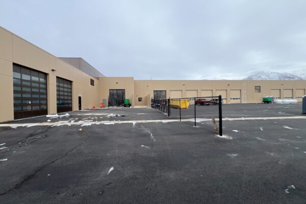 Exterior View Of A Commercial Building With A Fenced Parking Area